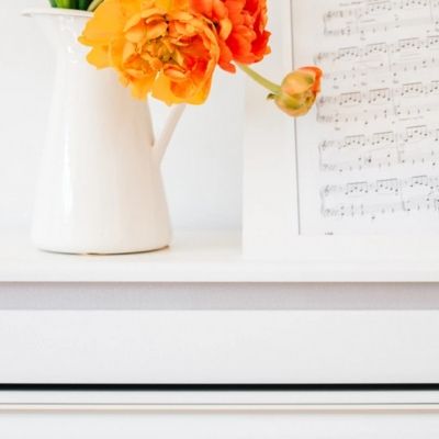 flowers in vase and sheet music on top of piano